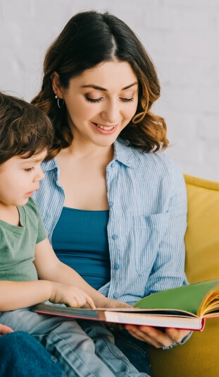 A young babysitter reading a book to a little boy